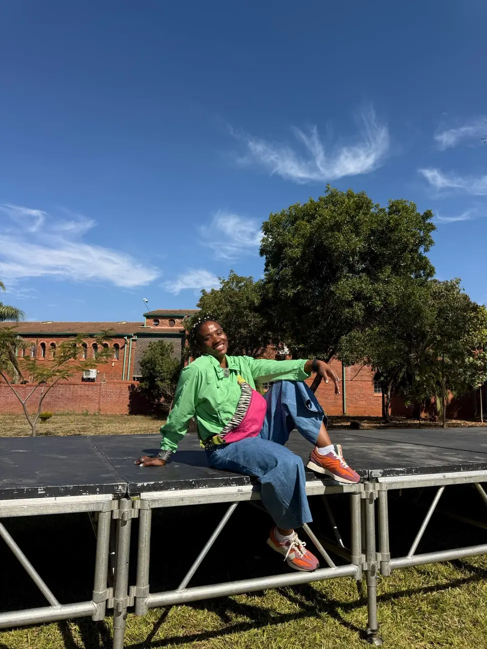Tanya in a bright green jacket and pink sneakers, smiling outdoors